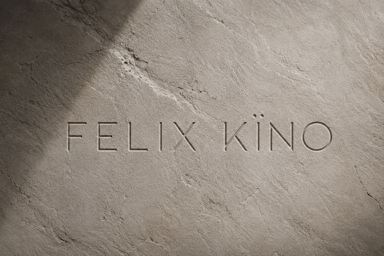 The words FELIX KÏNO engraved into a sunlit stone surface